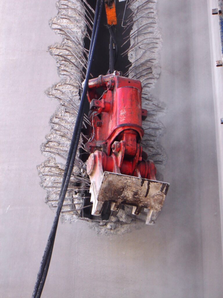 A crusher from Jet Demolition suspended from a crane to-crush concrete silo walls